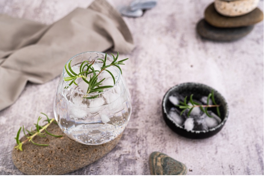 A glass of water with ice and rosemary
