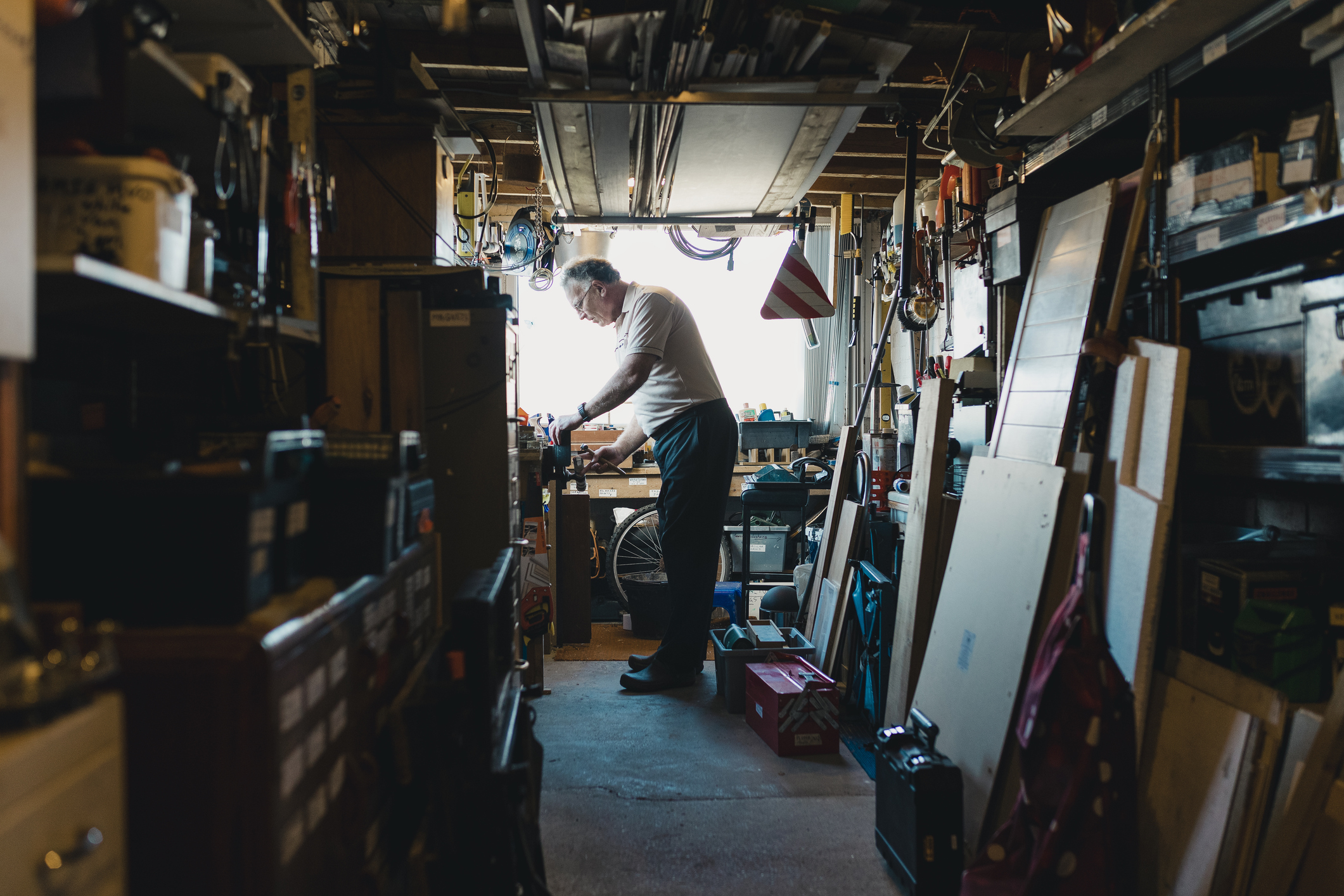 Senior man is working in his shed on a woodwork project. He is fatsening something in to a vice.