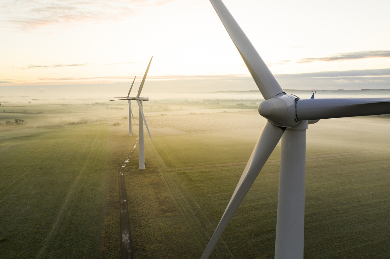 Aerial view of three wind turbines in the early morning fog at sunrise in the English countryside